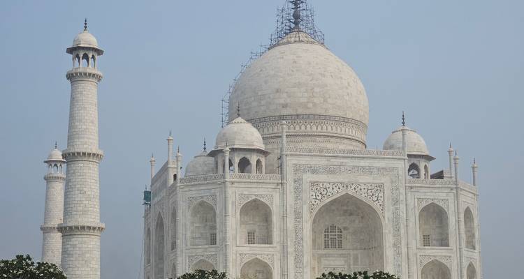 The Taj Mahal under a clear sky with its minarets.
