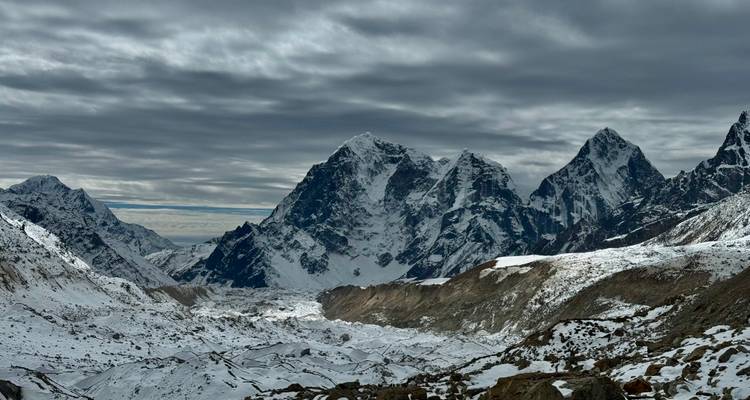 Montagnes enneigées sous un ciel nuageux.