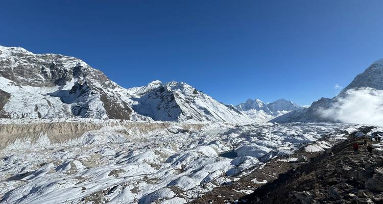 Vue large d'un paysage enneigé avec des montagnes sous un ciel bleu dégagé.