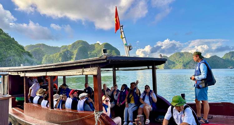 Touristen auf einem Boot in einer malerischen Bucht mit Hügeln.