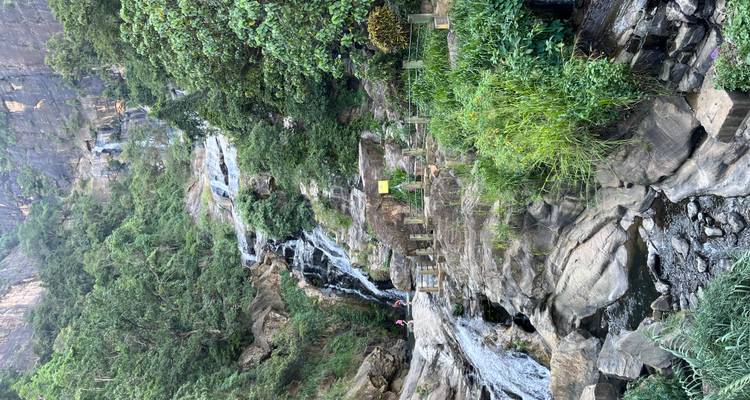 Ein Wasserfall, der einen felsigen Hügel hinunterstürzt, mit Grün an den Seiten.