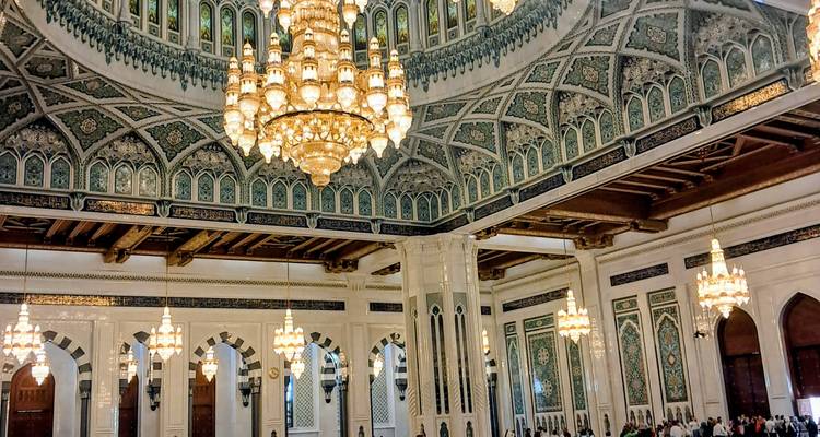 Interieur van een grote moskee met kroonluchters en ingewikkelde architectuur.