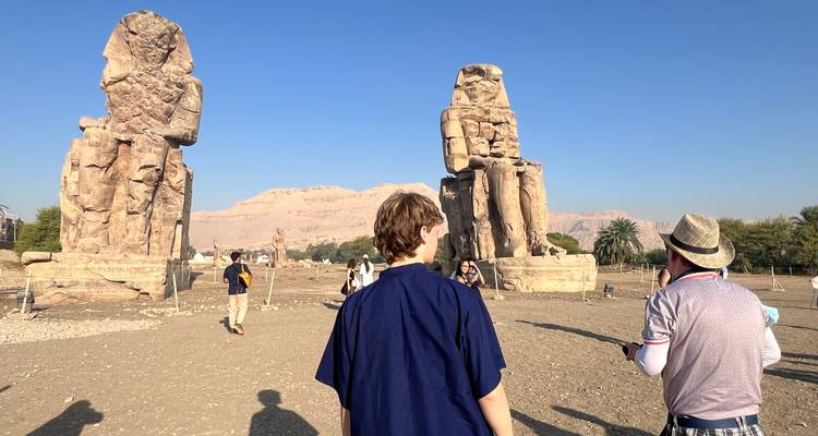 Toeristen die de Kolossi van Memnon bezoeken met bergen op de achtergrond.