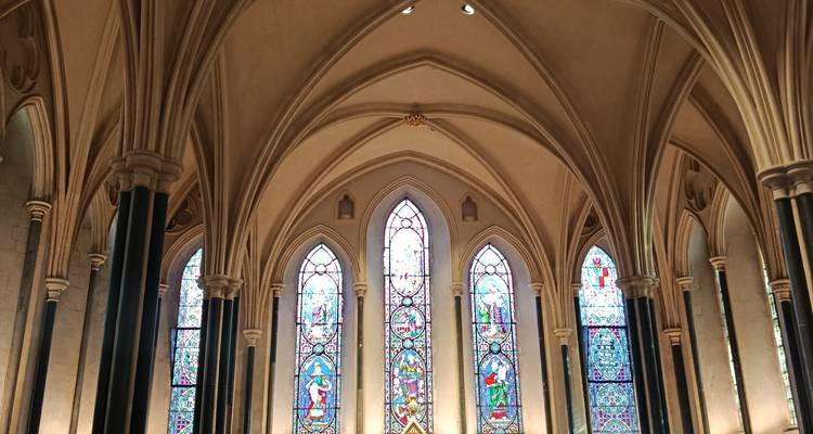 Interieur van een kerk met glas-in-loodramen en bogen.