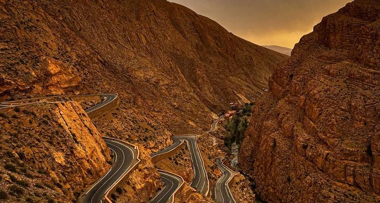 Kronkelende bergweg door ruig terrein bij schemering.