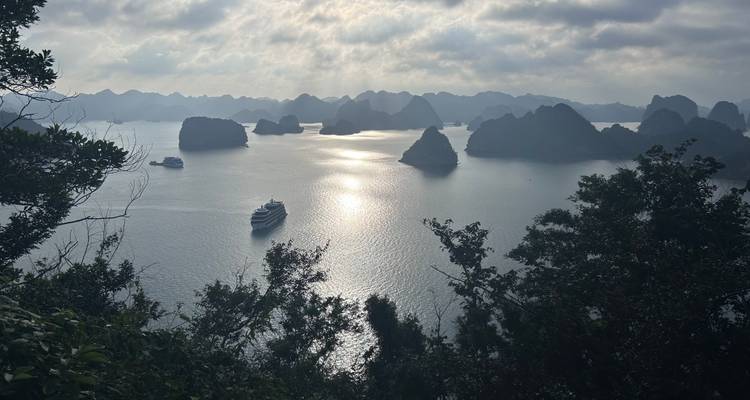 Schilderachtig uitzicht op een baai met boten en verre eilanden onder een dramatische hemel.
