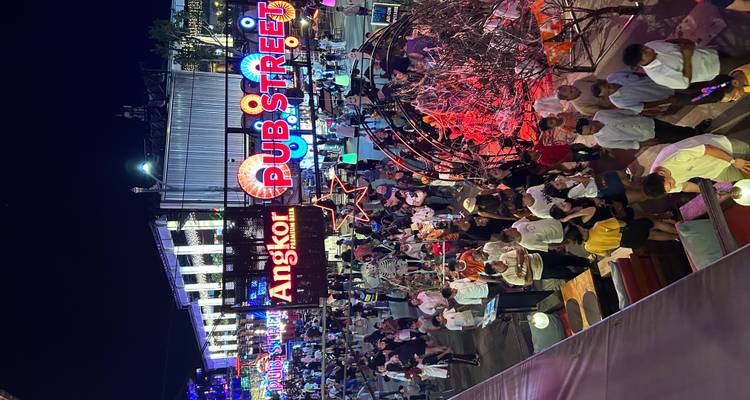 Nachtscène van een drukke straat verlicht met kleurrijke lichten en veel mensen.