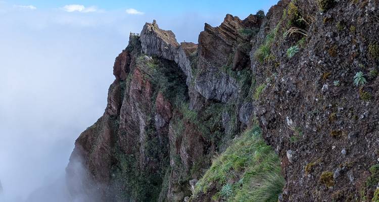 Een schilderachtig uitzicht op een rotsachtige klif met een klein gebouw op de top, omringd door mist.