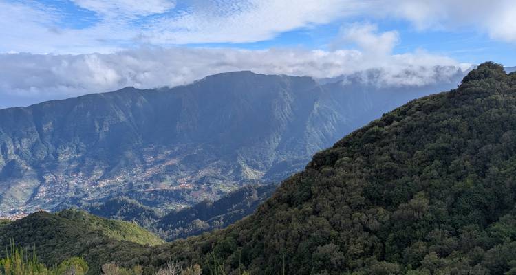 Un vaste paysage montagneux avec une vue sur des vallées lointaines and des nuages.