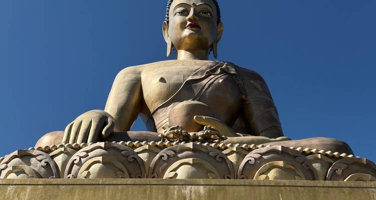 Une grande statue de Bouddha contre un ciel bleu clair.
