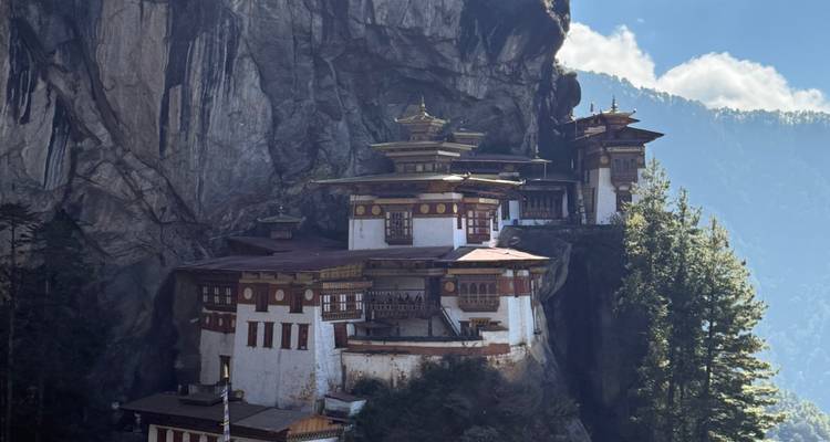 Een klooster gebouwd in een klif met een bosachtige achtergrond.