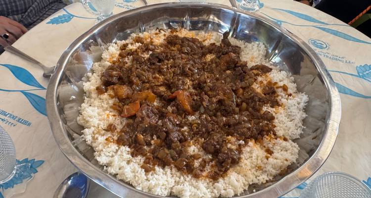 Große Servierplatte gefüllt mit Reis und Eintopf auf einem Esstisch.