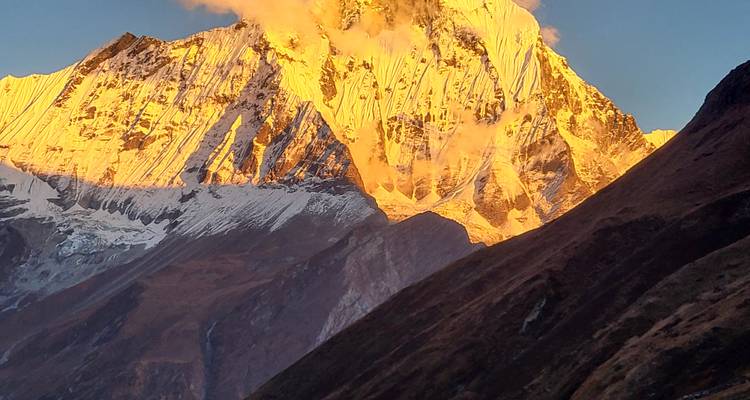 Un sommet de montagne enneigé baigné de lumière dorée.