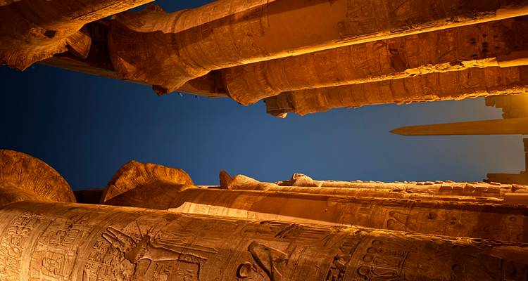 Blick auf antike Säulen und einen Obelisk bei Nacht.