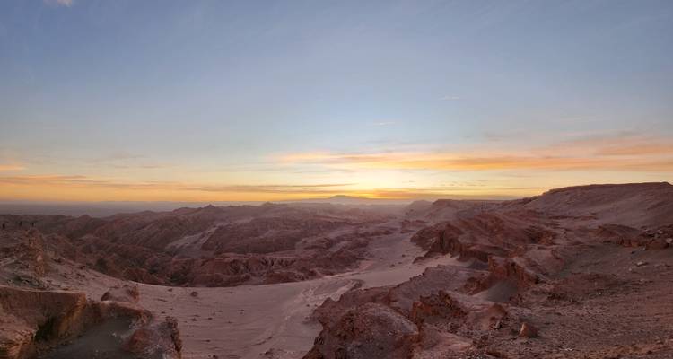 Zonsondergang over een woestijnlandschap met rotsachtig terrein.