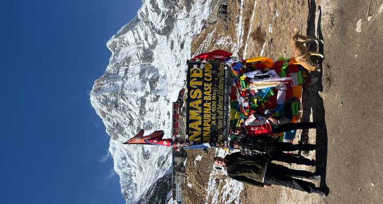 Groep mensen bij Annapurna Base Camp met kleurrijke vlaggen en een bergachtergrond.