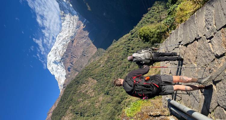 Wandelaars die lopen op een bergpad met een besneeuwde top in de verte.