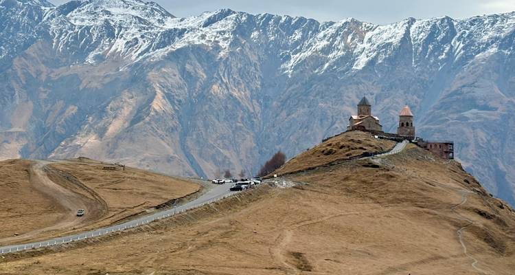 Iglesia en la cima de la colina con montañas nevadas al fondo.