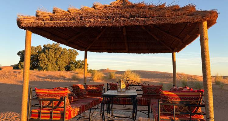 Gazebo dans le désert avec sièges et décoration traditionnels.