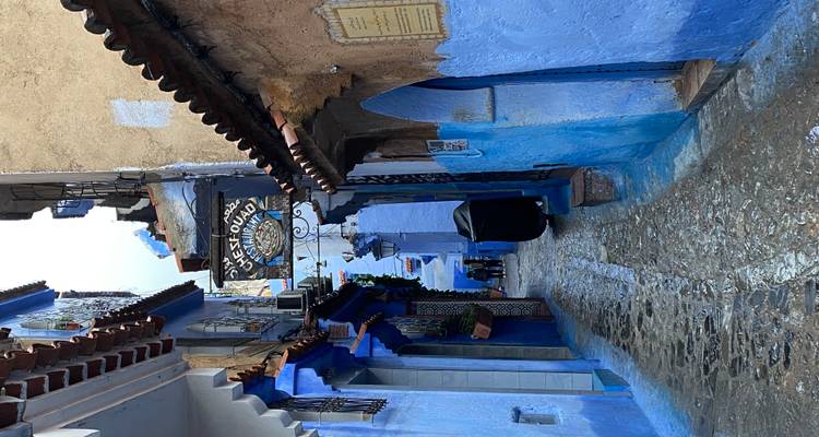 Narrow alleyway with blue-washed walls in a town.