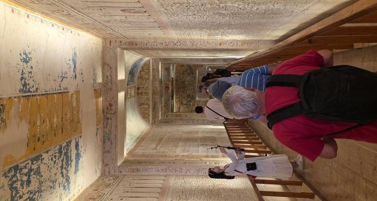 Visitantes caminando por una tumba con paredes jeroglíficas.