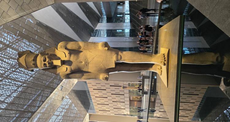 Gran estatua de un faraón egipcio dentro de un museo moderno.