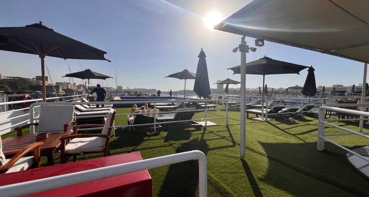 Día soleado en la cubierta de un crucero con tumbonas y sombrillas.