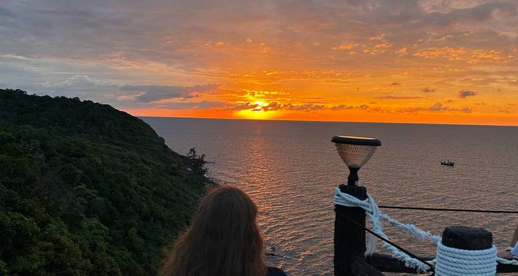 Zonsondergang boven de oceaan met uitzicht vanaf een dek.
