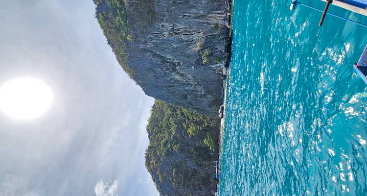 Une journée ensoleillée avec des eaux bleues claires et des formations rocheuses escarpées.