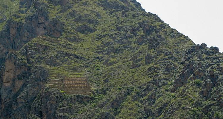 Terrazas de piedra construidas en una pendiente montañosa empinada y verde.