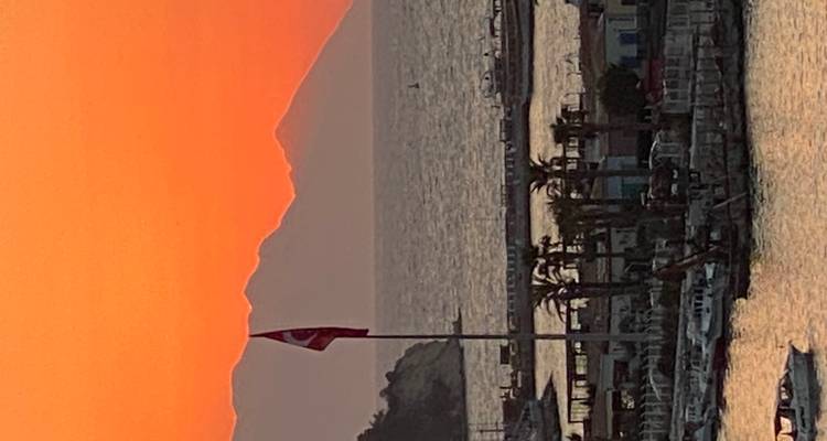 Silhouet van een landschap bij zonsondergang met zeezicht.