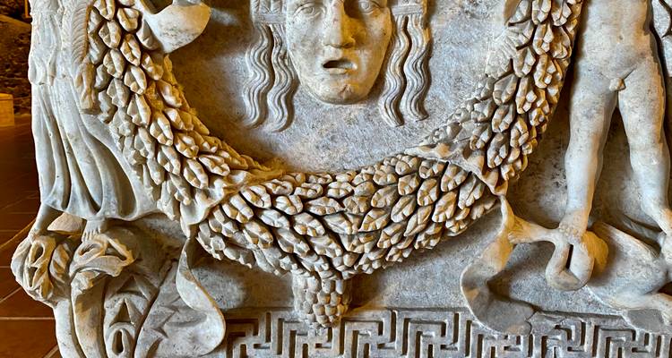 Steenbeeldhouwwerk met godheid en druiven motief.