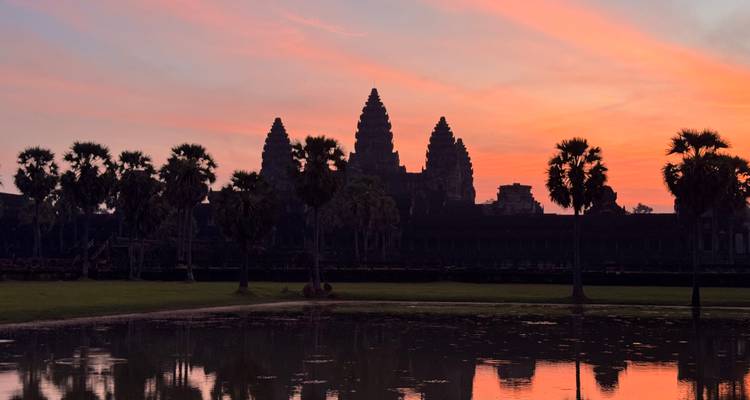 Angkor Wat tijdens zonsondergang met warme tinten die weerkaatsen in het water.