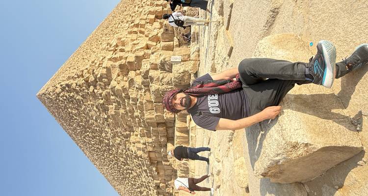 Mann sitzt vor einer Pyramide.