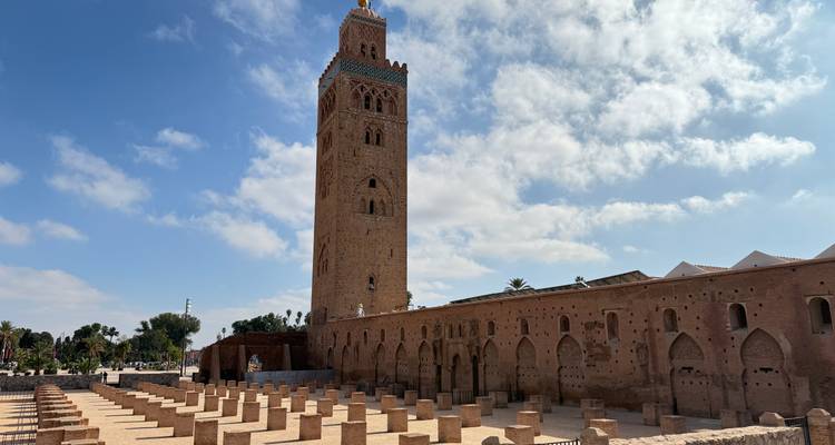 Een hoge historische toren en een open binnenplaats onder een blauwe hemel.