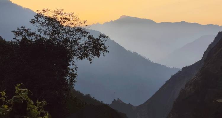 Una vista serena de montañas con neblina y un amanecer dorado.