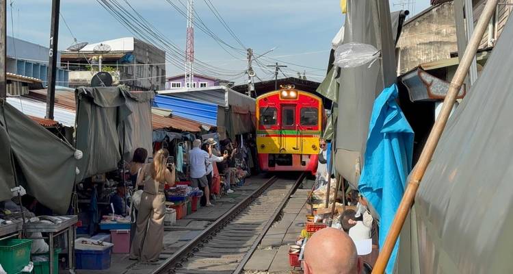 Trein die door een drukke marktstraat rijdt.