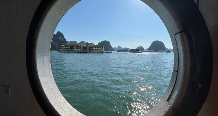 View from a ship's porthole capturing boats and karst landscapes.