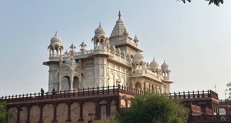 Een prachtig wit marmeren gebouw met koepeldaken en een grote veranda.