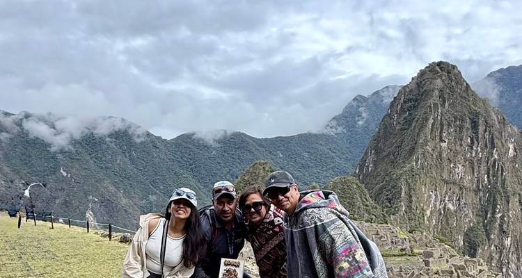 Vier mensen poseren voor het prachtige bergachtige uitzicht van Machu Picchu.