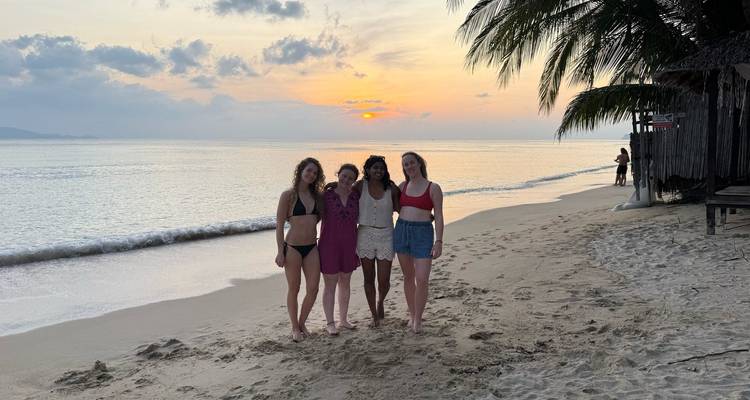 Quatre personnes sur une plage au coucher du soleil.