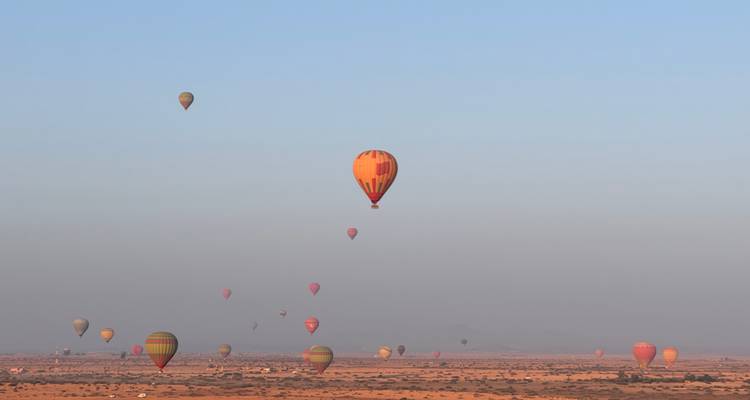 Heteluchtballonnen boven een woestijnlandschap.