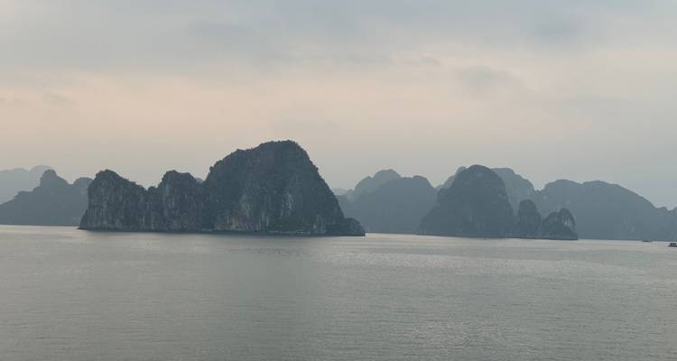 Vista de islas de piedra caliza en una bahía tranquila con cielos nublados.