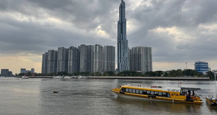Paisaje urbano con modernos edificios de gran altura y un río con embarcaciones.