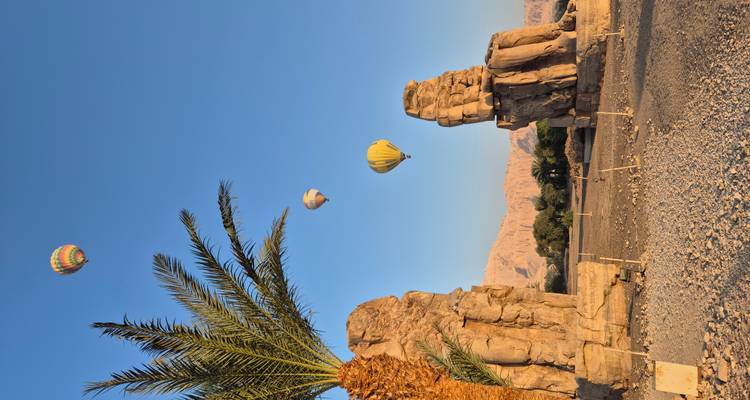 Heteluchtballonnen boven oude Egyptische standbeelden.