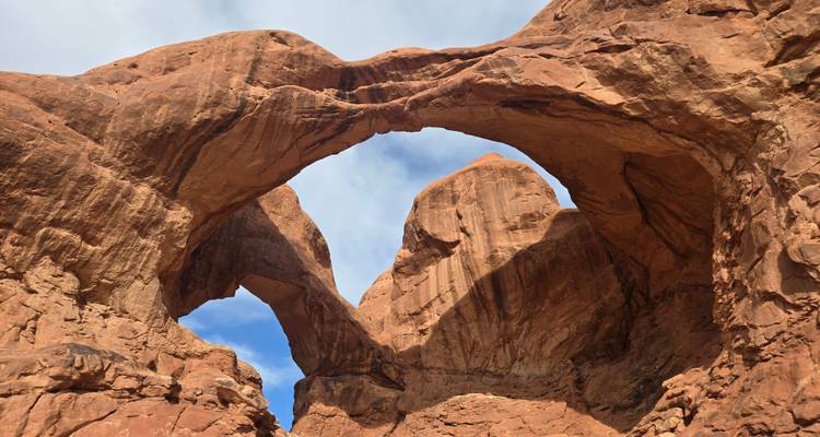 Rotsenbogen in een woestijnlandschap onder een blauwe hemel.