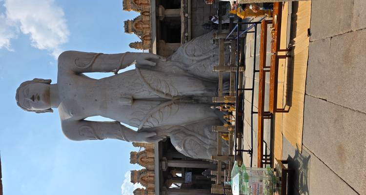 Estatua masiva de piedra de una figura de pie en un patio abierto.