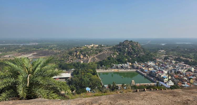 Vista aérea de una colina rocosa con estructuras y vegetación exuberante.