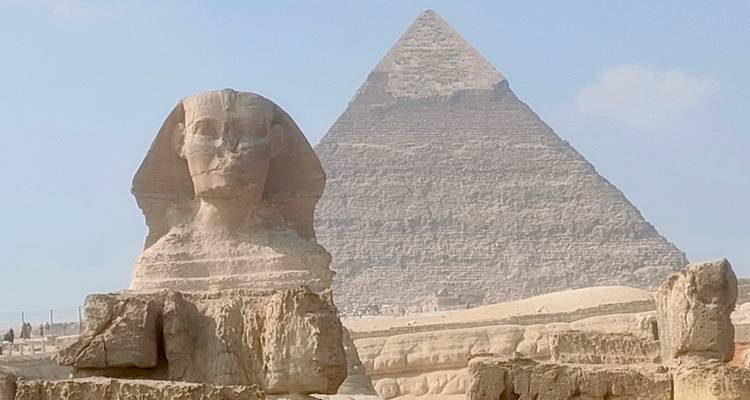 Una famosa esfinge y pirámide del antiguo Egipto bajo un cielo azul.