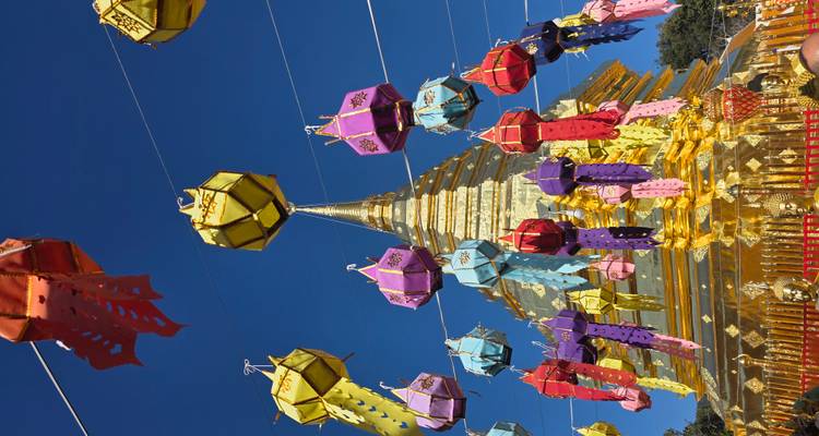 Goldener Tempel mit bunten Laternen vor einem klaren blauen Himmel.